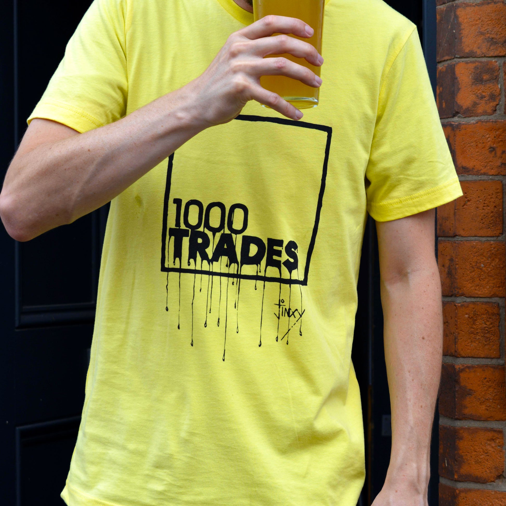 Model wearing a yellow 1000 Trades t-shirt